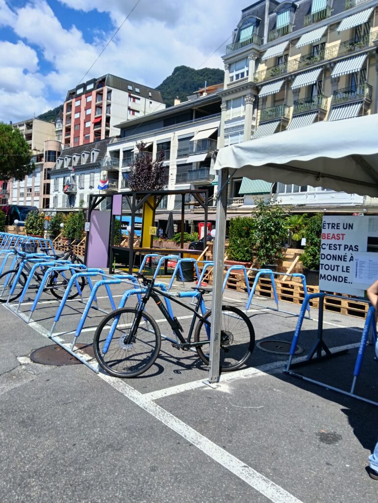 Fila di biciclette blu acceso parcheggiate in una rastrelliera in una piazza urbana soleggiata con condomini e una collina sullo sfondo
